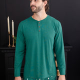 Man standing in a black room while wearing the Men's Long Sleeve Henley Top in Emerald