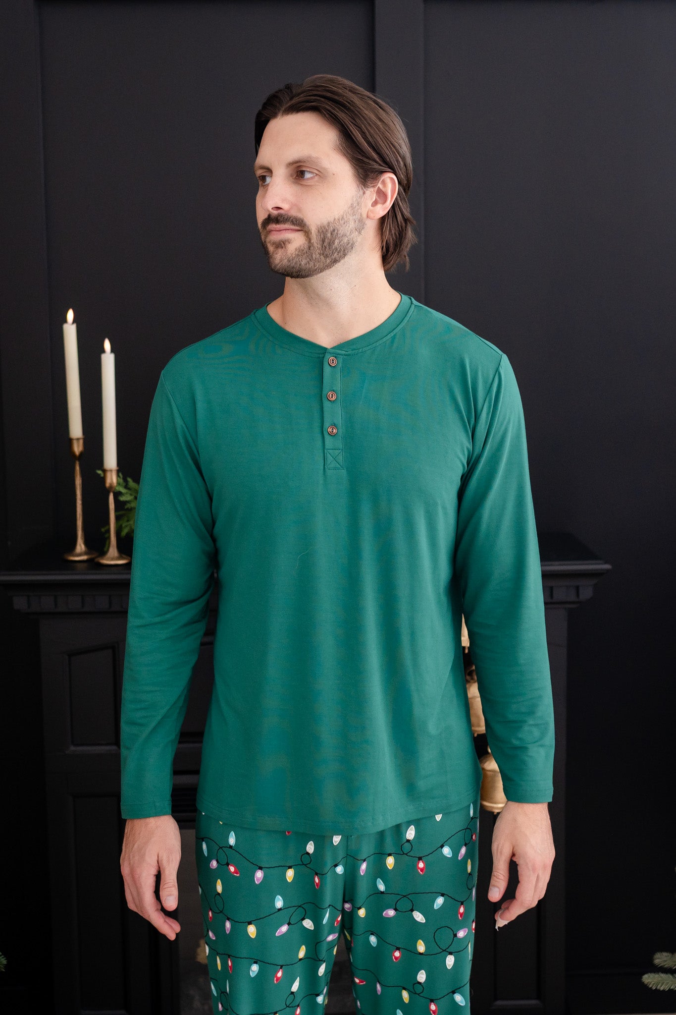 Man standing in a black room while wearing the Men's Long Sleeve Henley Top in Emerald