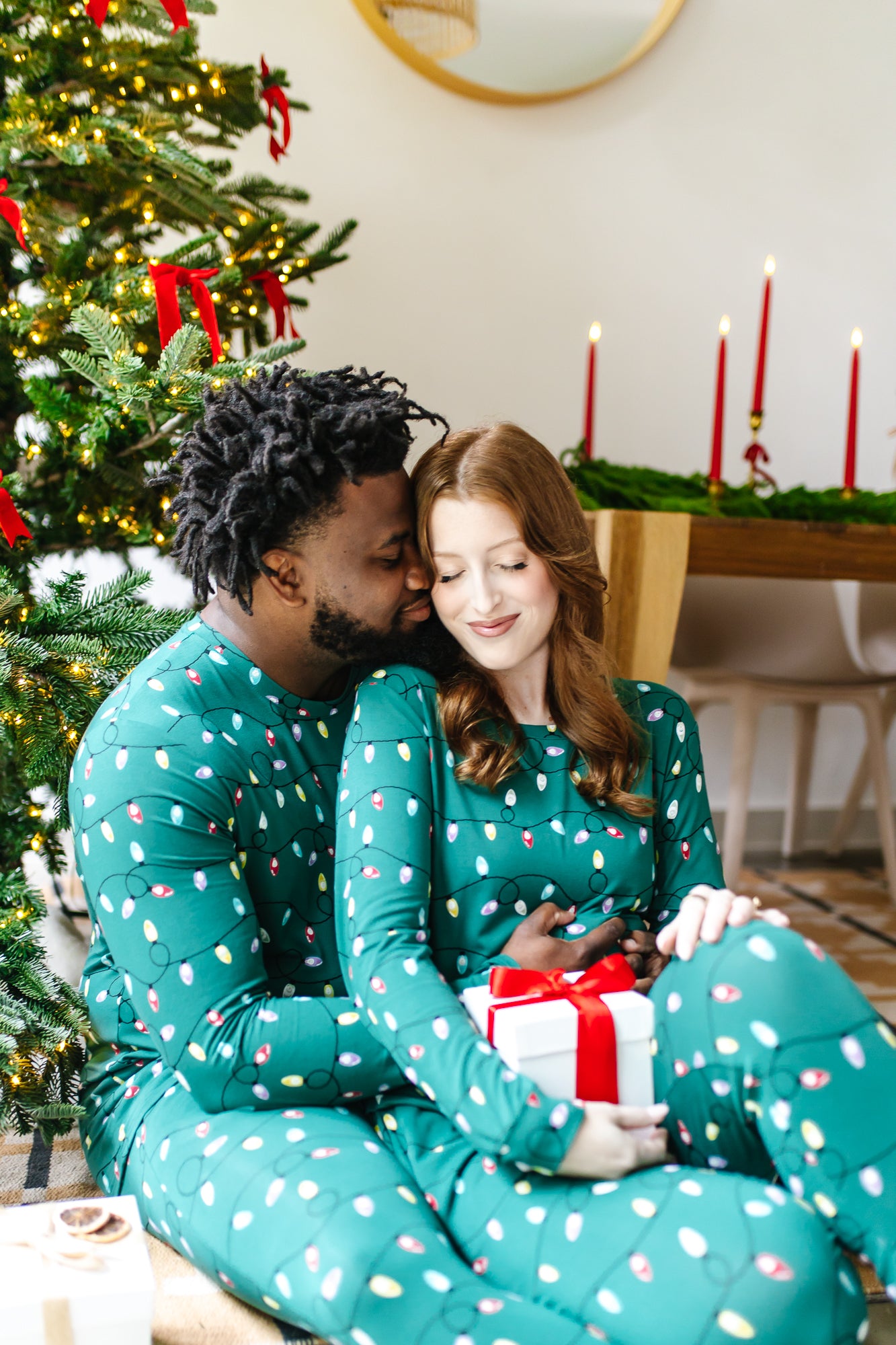Couple snuggling in front of a Christmas tree wearing matching Jogger Sets in  Merry and Bright