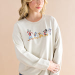 Woman standing in front of a beige back ground looking to the side while modeling the Women's Sweatshirt in Mickey and Friends on Ecru paired with dark wash jeans ::: Model is 5'7" wearing size S ///