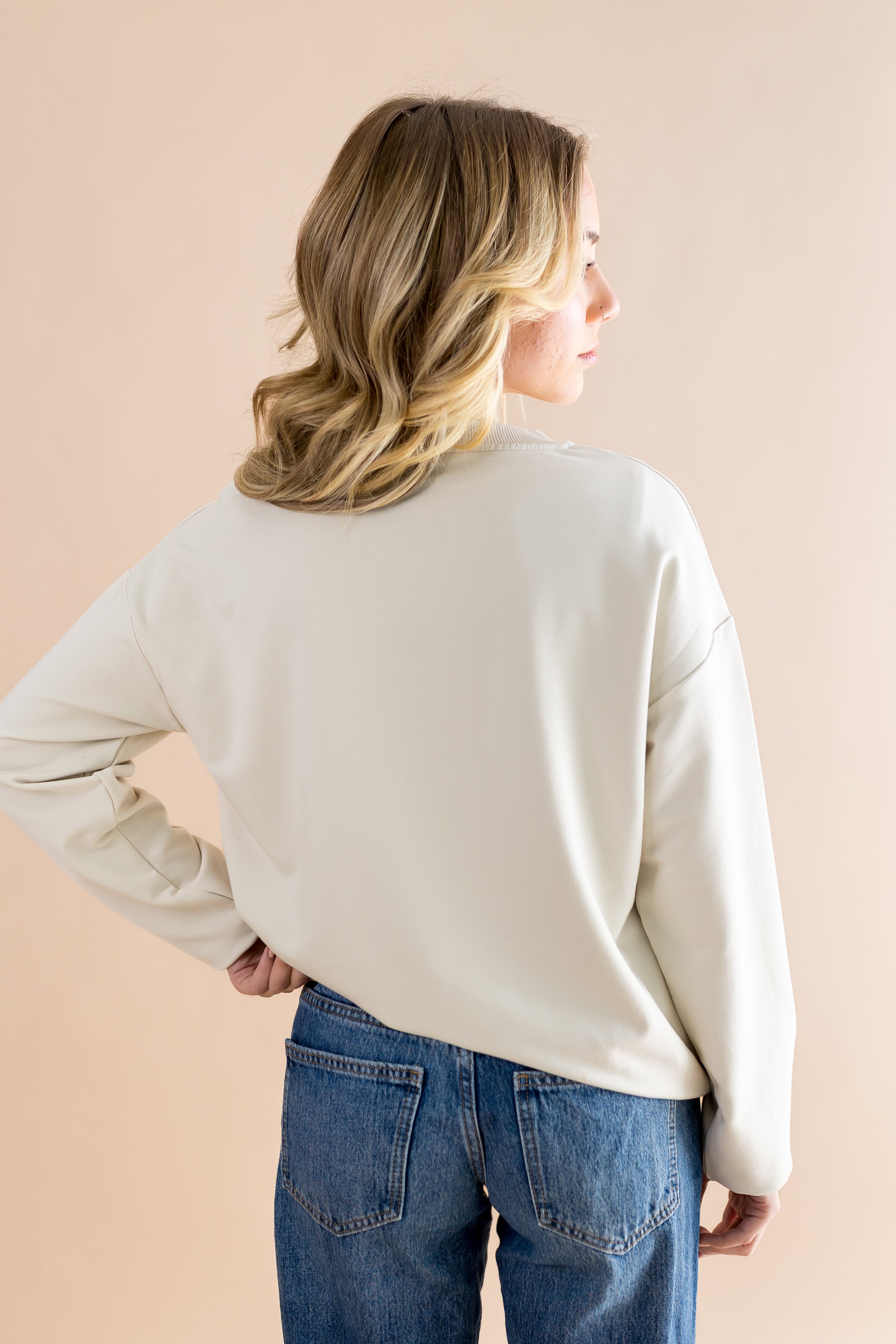 Model showcasing the back side of the Women's Sweatshirt in Mickey and Friends on Ecru