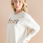 Women modeling the Women's Sweatshirt in Mickey and Friends on Ecru with hand in her back jean pocket