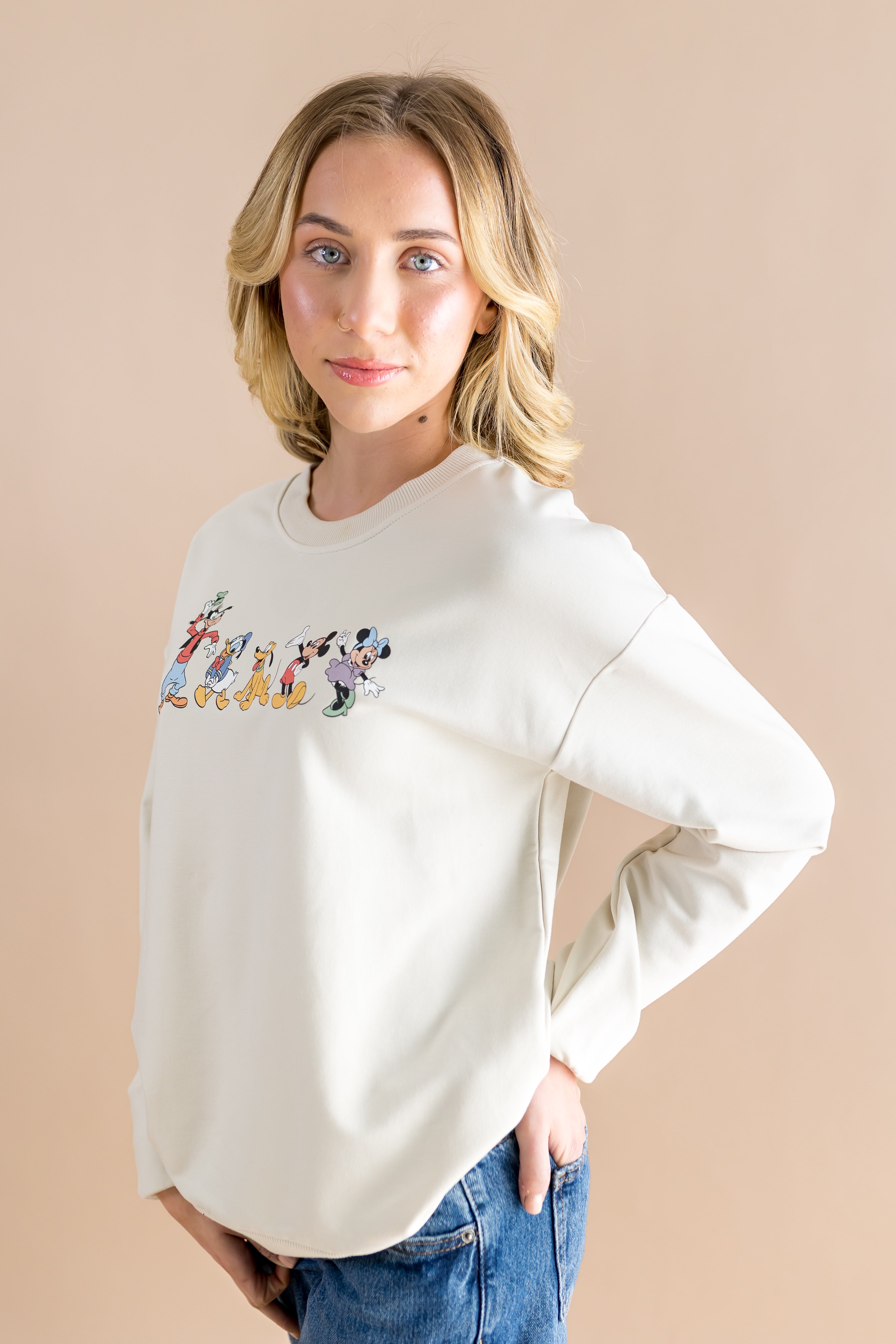 Women modeling the Women's Sweatshirt in Mickey and Friends on Ecru with hand in her back jean pocket