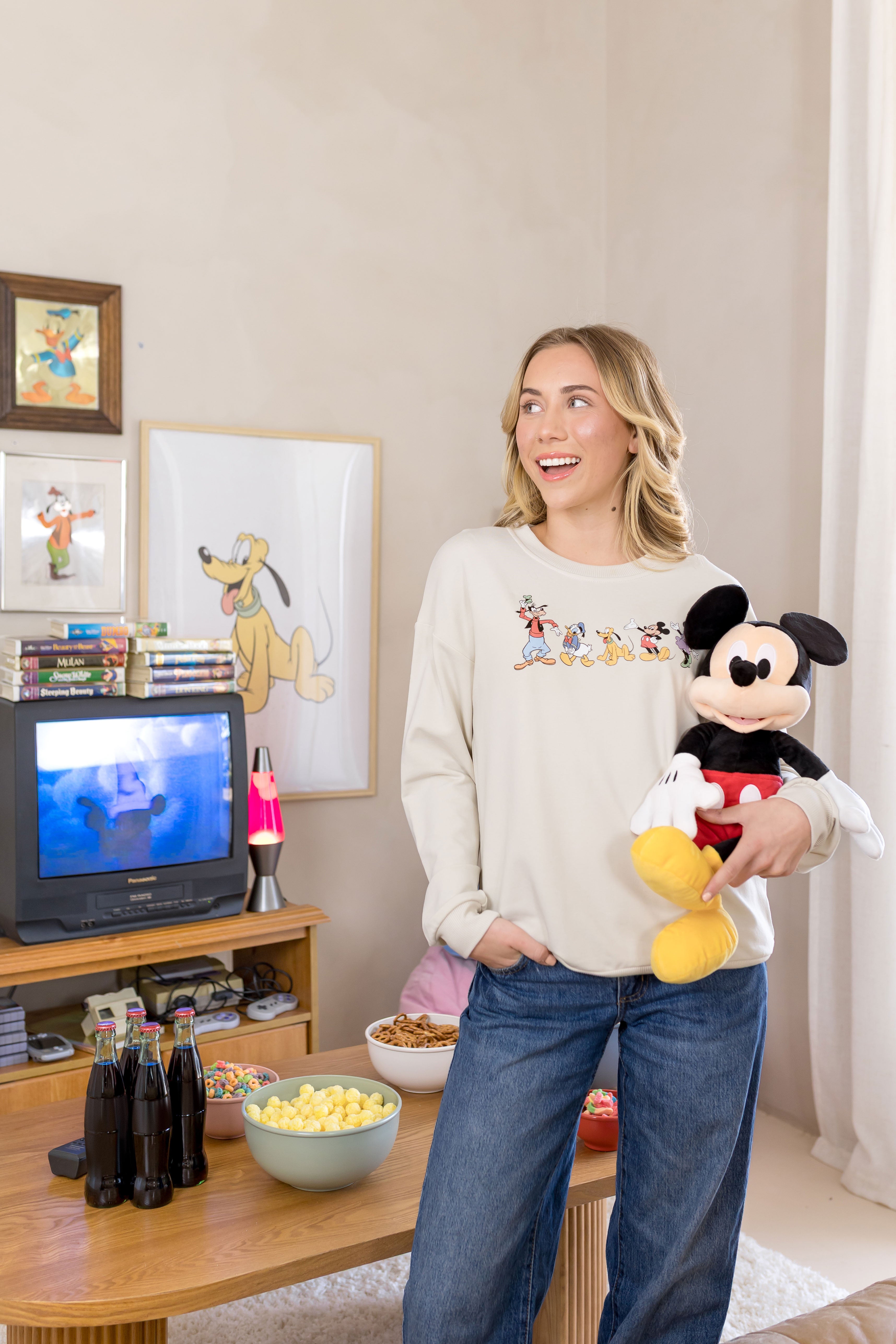 Woman wearing a sweatshirt with mickey and friends graphic on the front