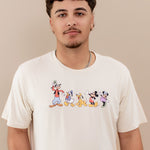 Close up of the Men's Crew Neck Tee in Mickey and Friends on Ecru on a male model standing in front of a beige background