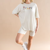 Smiling woman standing with one  leg folded up while modeling the Women’s Biker Short Set in Mickey and Friends on Ecru