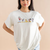 Model standing in front of a beige back ground while wearing the Women's Graphic Tee in Mickey and Friends on Ecru with her hands behind her back paired with jean shorts

::: Model is 5' wearing size XS ///