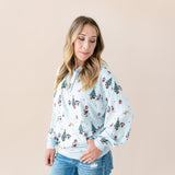 Woman posing Women's Hoodie in Mickey & Friends Christmas print on blue jeans on a beige background