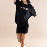 Model with arm on her forehead while wearing the Women’s Biker Short Set in Mickey and Friends on Midnight paired with white sneakers