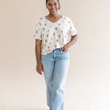 Model standing in front of a beige background wearing the Women's Relaxed Fit V-Neck in Mickey Mouse and Friends paired with light washed cropped jeans

::: Model is 5'1" wearing size S ///