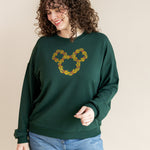 Women smiling in Women's Sweatshirt in Mickey Christmas Wreath print on Cypress color over blue jeans on a beige background