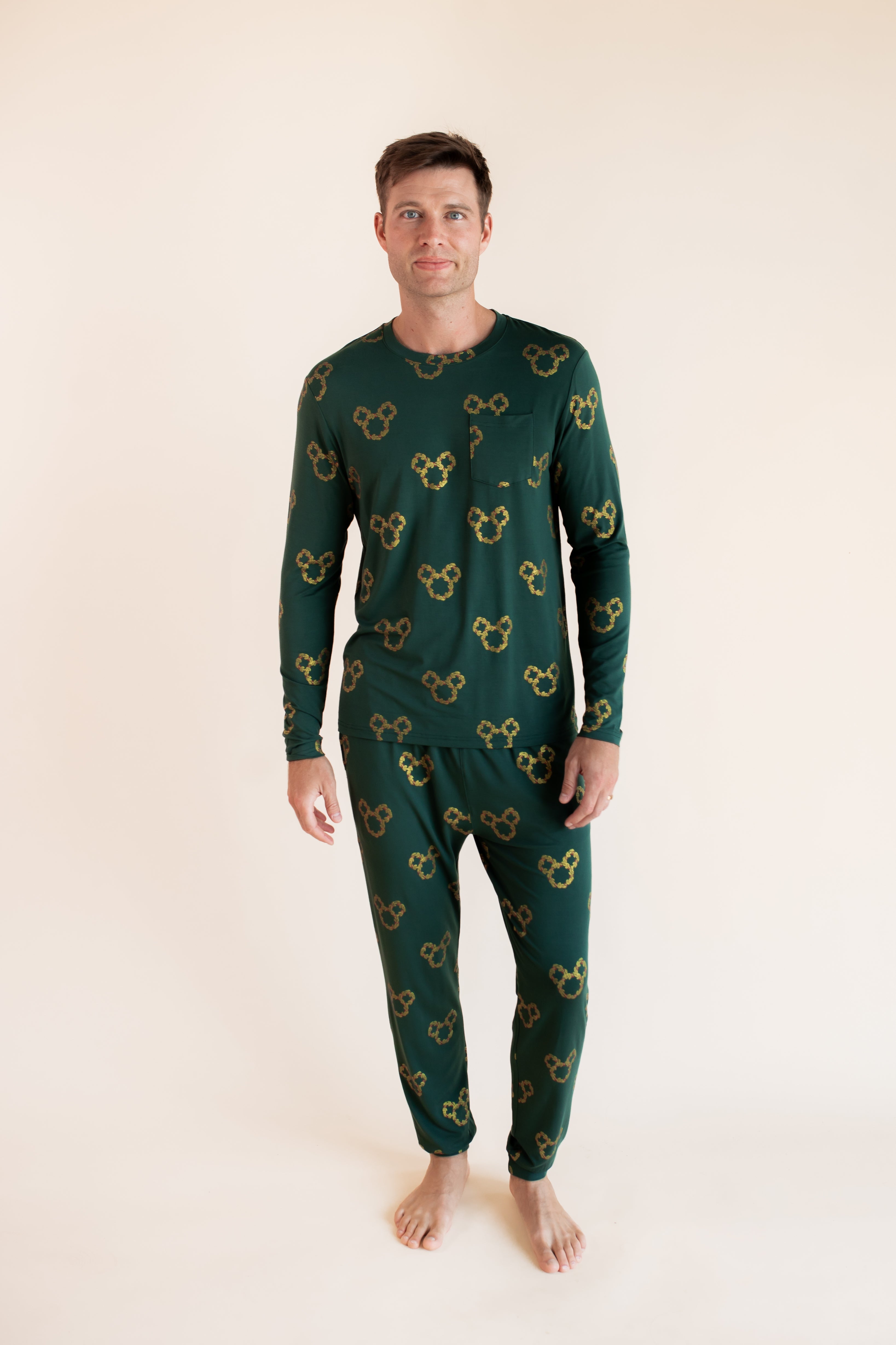 Man wearing Men's Jogger Set in Mickey Christmas Wreath print on a beige background
