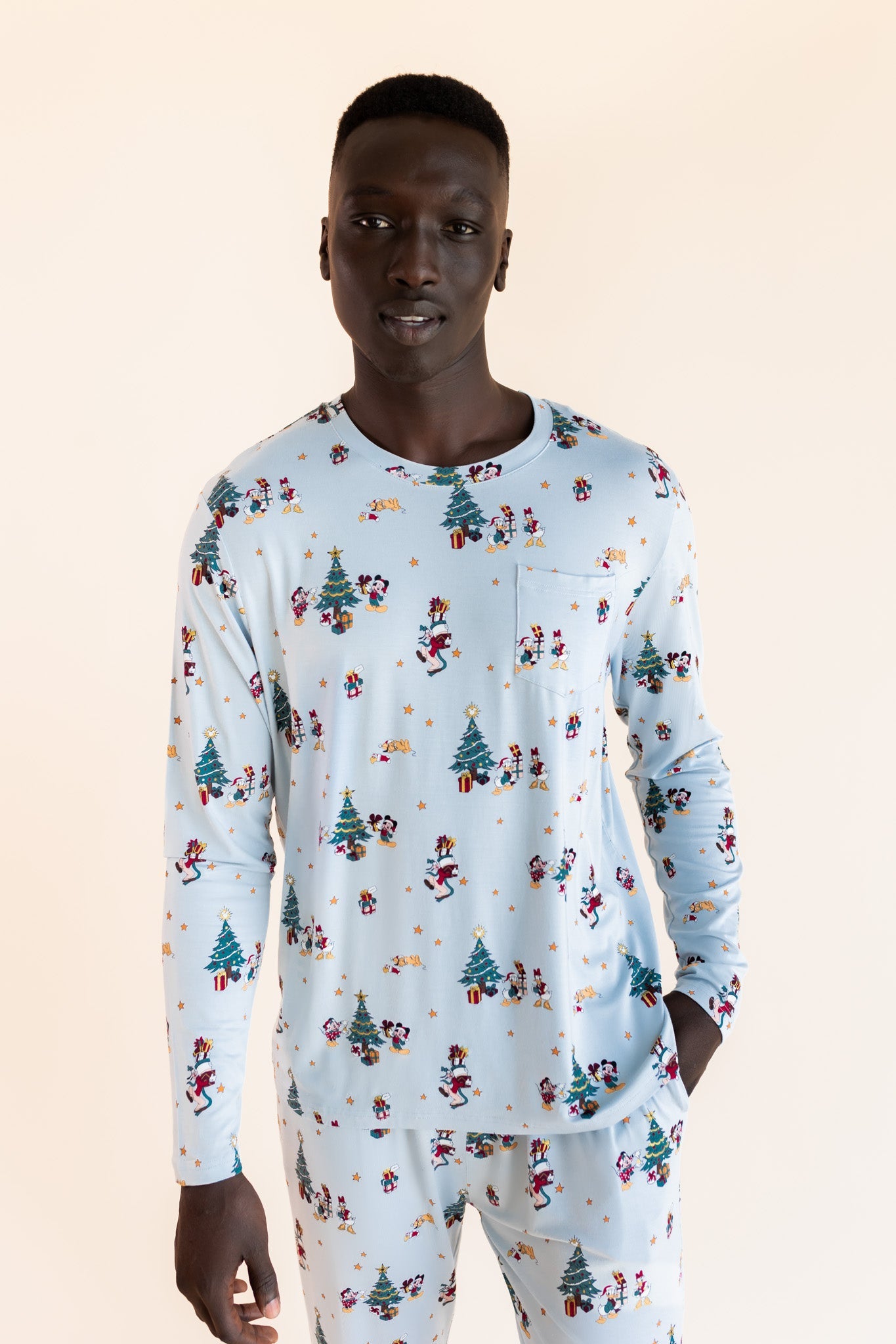Man wearing Men's Jogger Set in Mickey & Friends Christmas print on a beige background