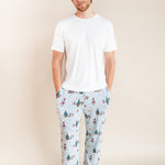 Man wearing Men's Lounge Pants in Mickey & Friends Christmas print over white T-shirt on a beige background