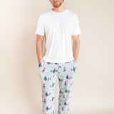 Man wearing Men's Lounge Pants in Mickey & Friends Christmas print over white T-shirt on a beige background