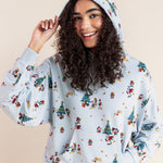 Woman wearing Women's Hoodie in Mickey & Friends Christmas print on blue jeans on a beige background
::: Model is 5'10" wearing size XS ///