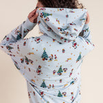 Woman showcasing the hoodie of Women's Hoodie in Mickey & Friends Christmas print on blue jeans on a beige background