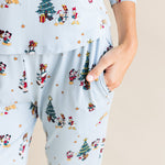 Woman showcasing pockets on Women's Jogger Pajama Set in Mickey & Friends Christmas print on a beige background