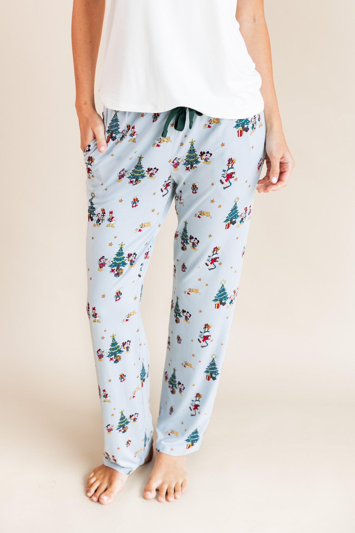 Modal wearing Women's Lounge Pants in Mickey & Friends Christmas print under white T-shirt on a beige background
::: Model is 5'10" wearing size S ///