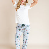 Woman posing in Women's Lounge Pants in Mickey & Friends Christmas print under white T-shirt on a beige background