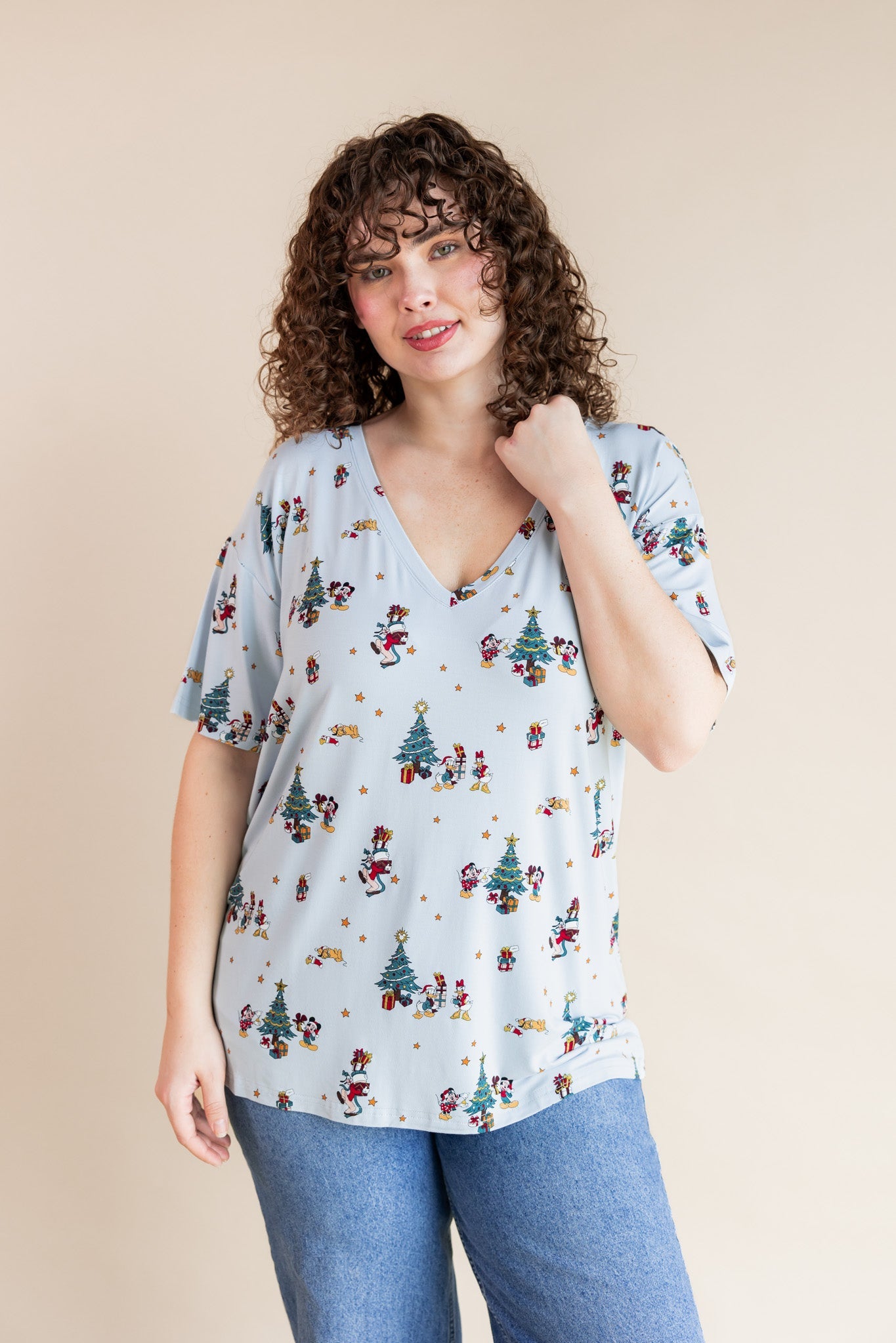 Woman wearing Women's Oversized V-Neck Tee in Mickey & Friends Christmas print over blue jeans on a beige background
::: Model is 5'10" wearing size XL ///