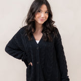 Woman wearing a black cardigan against a plain background