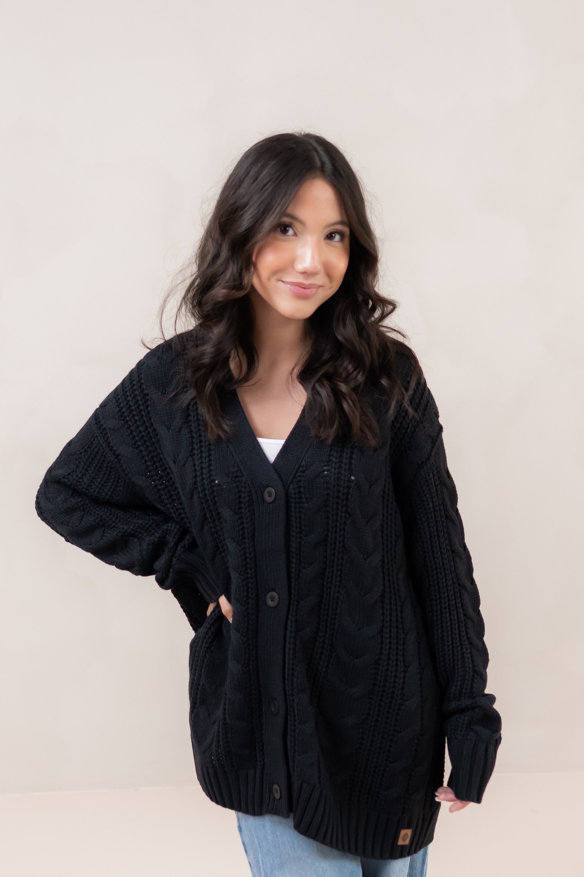 Woman wearing a black cardigan against a plain background