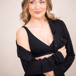 Woman in black cross front bralette with unbottoned pajama top