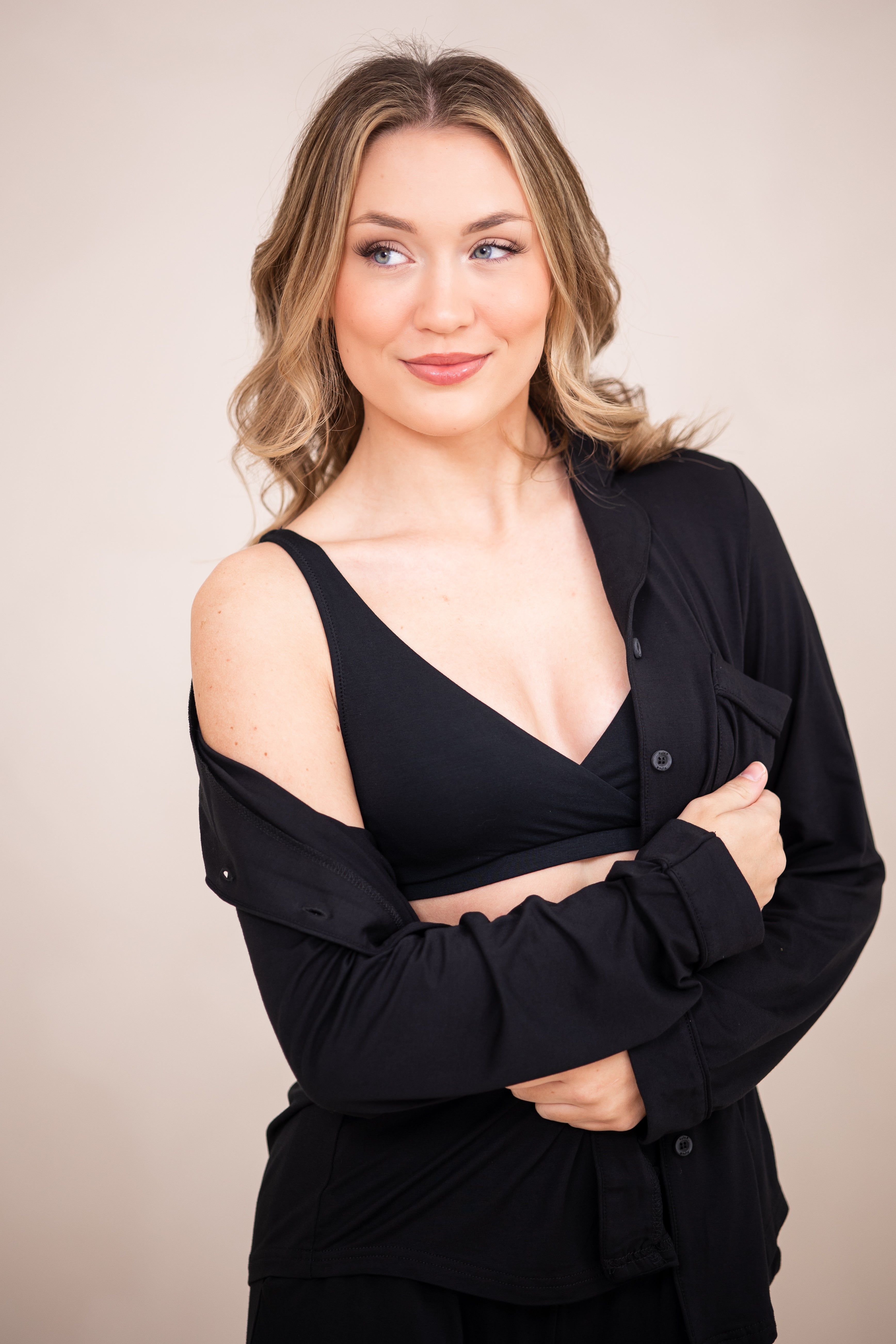 Woman in black cross front bralette with unbottoned pajama top