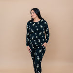 Woman wearing a Big Midnight Magnolia jogger pajama set against a beige background
