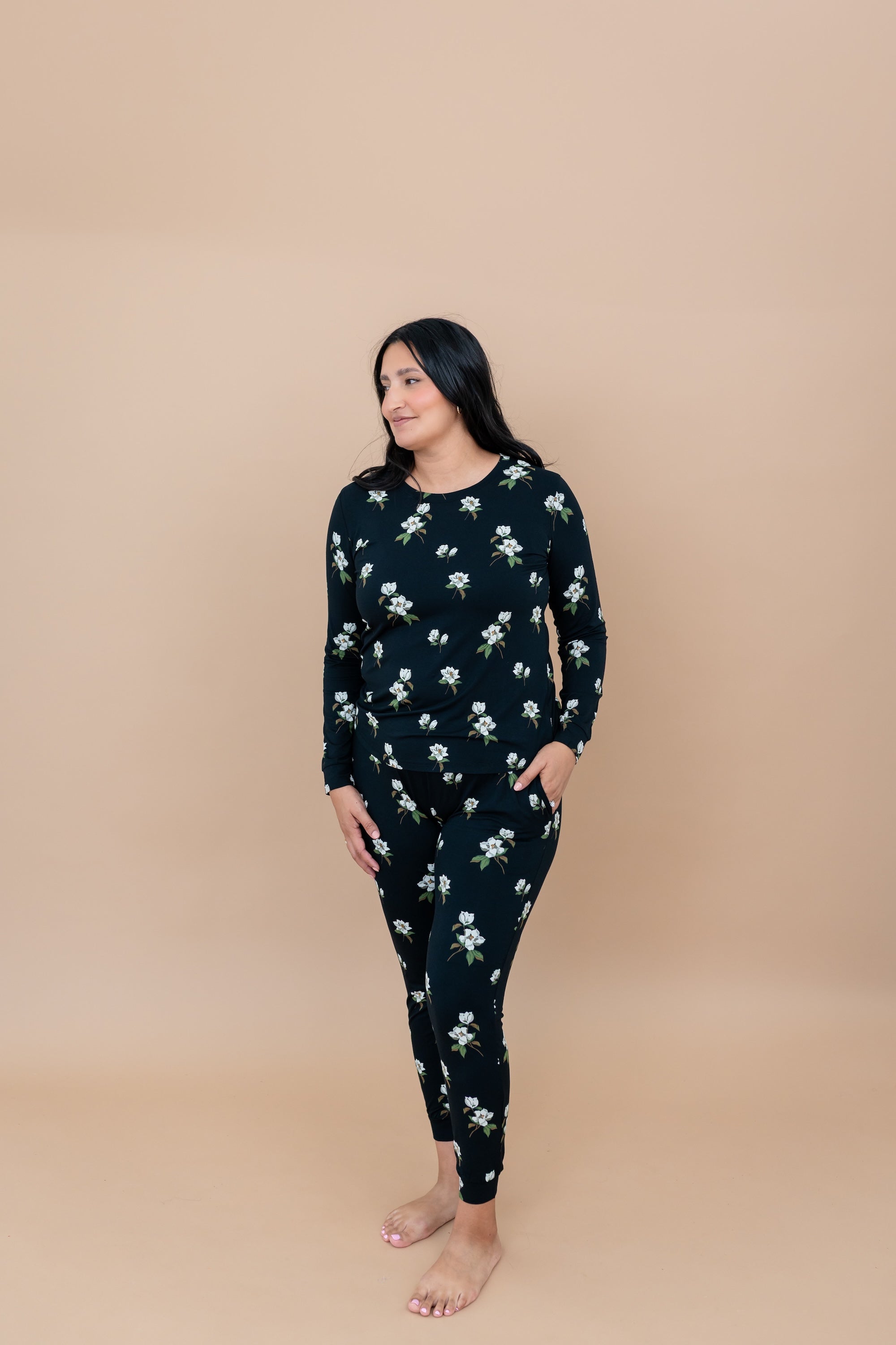 Woman wearing a Big Midnight Magnolia jogger pajama set against a beige background