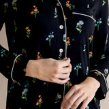 Model showcasing the front white buttons of Long Sleeve Women’s Nightshirt in Midnight Wildflower print on a beige background