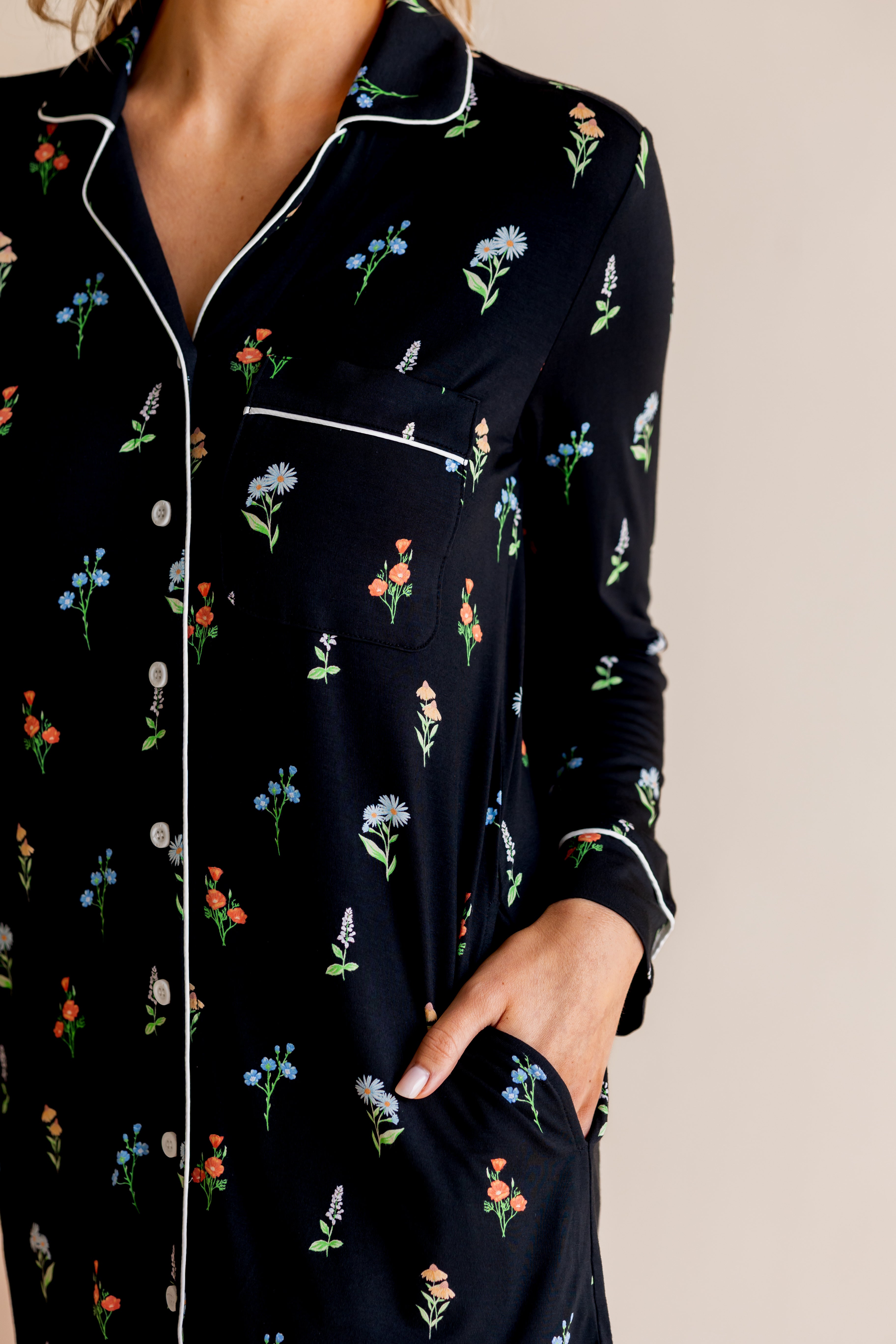 Model showcasing the pockets of Long Sleeve Women’s Nightshirt in Midnight Wildflower print on a beige background