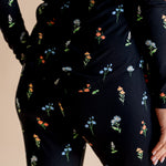 Model showing the back of Women's Jogger Pajama Set in Midnight Wildflower print on beige background