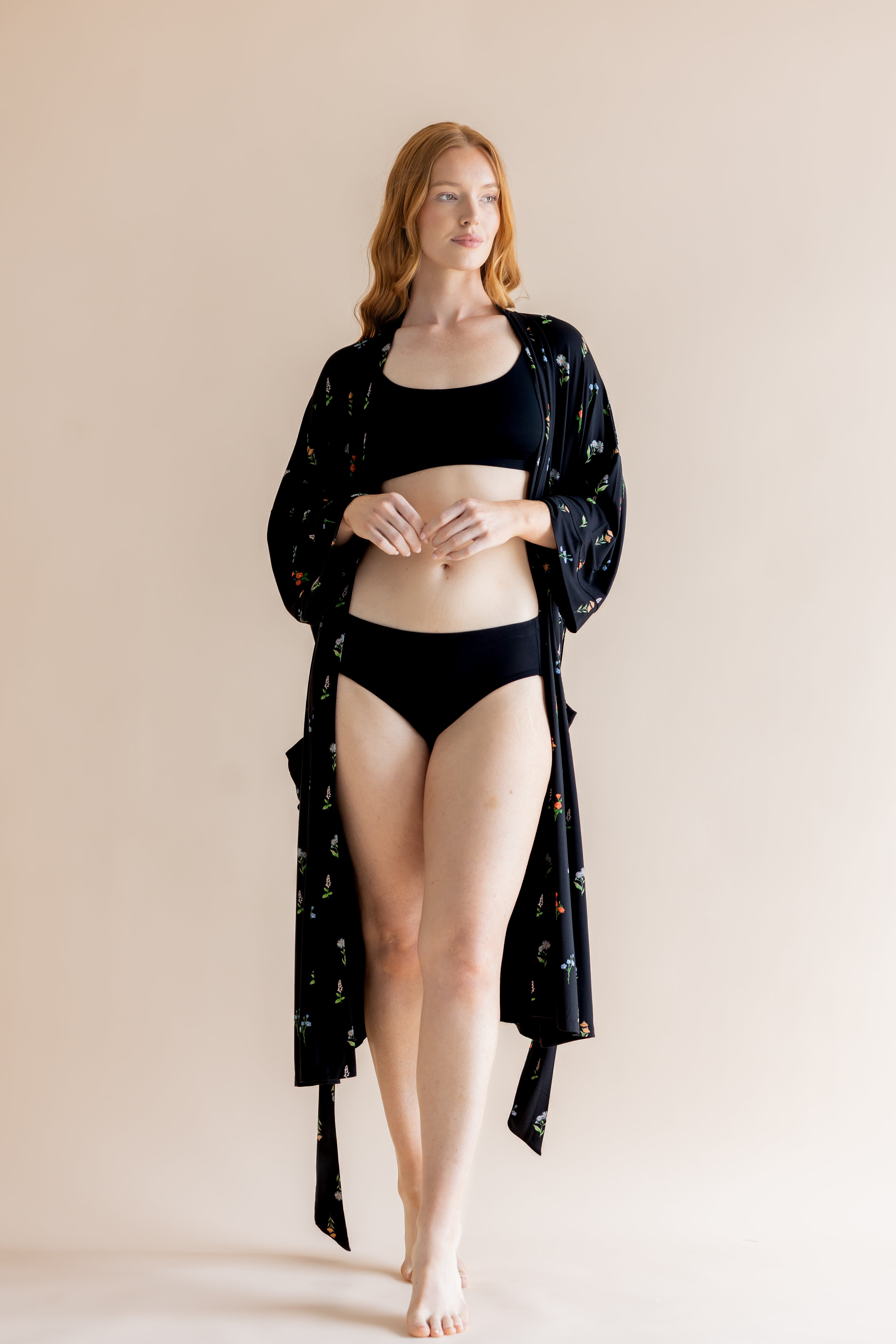 Model wearing black bra and underwear with Women’s Kimono Robe in Midnight Wildflower print on a beige background