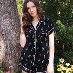 Model standing in front of a tree and greenery while wearing the Women's Short Sleeve Pajama Set in Midnight Wildflower ::: Model is 5'8" wearing size XS /// ---1615 1
