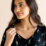 Model smiling in Women's Relaxed Fit V-Neck in Midnight Wildflower print on a beige background