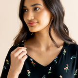 Model smiling in Women's Relaxed Fit V-Neck in Midnight Wildflower print on a beige background