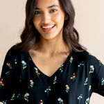 Model smiling in Women's Relaxed Fit V-Neck in Midnight Wildflower print on a beige background