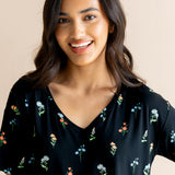 Model smiling in Women's Relaxed Fit V-Neck in Midnight Wildflower print on a beige background