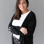 Female model wearing Bamboo Jersey Adult Cardigan in Midnight overtop a white shirt and faded black jeans