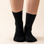 Black socks worn by a person on a beige background