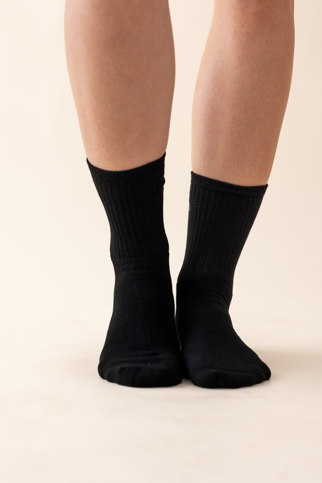 Black socks worn by a person on a beige background