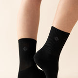 Black socks with kyte logo worn by a person on a beige background