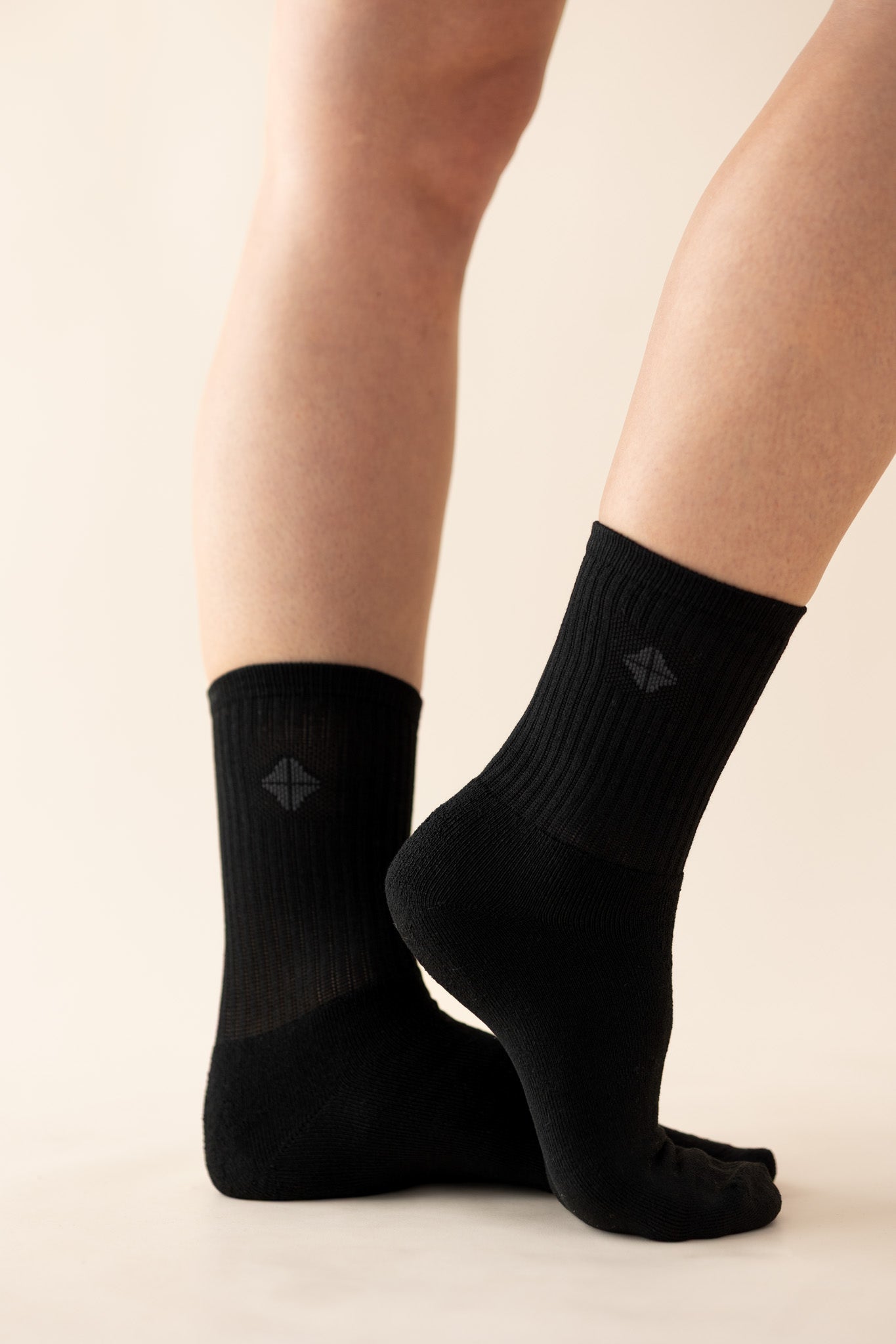Black socks with kyte logo worn by a person on a beige background