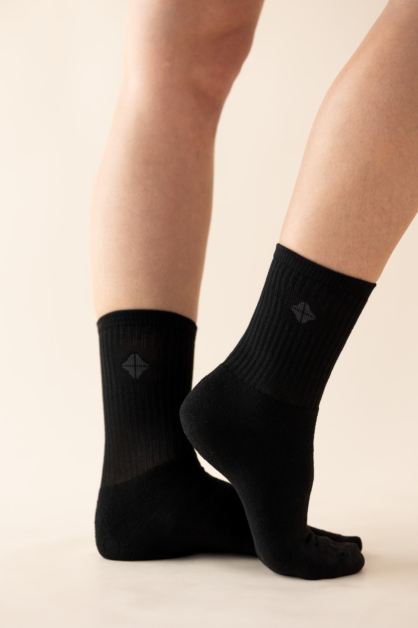 Black socks with kyte logo worn by a person on a beige background