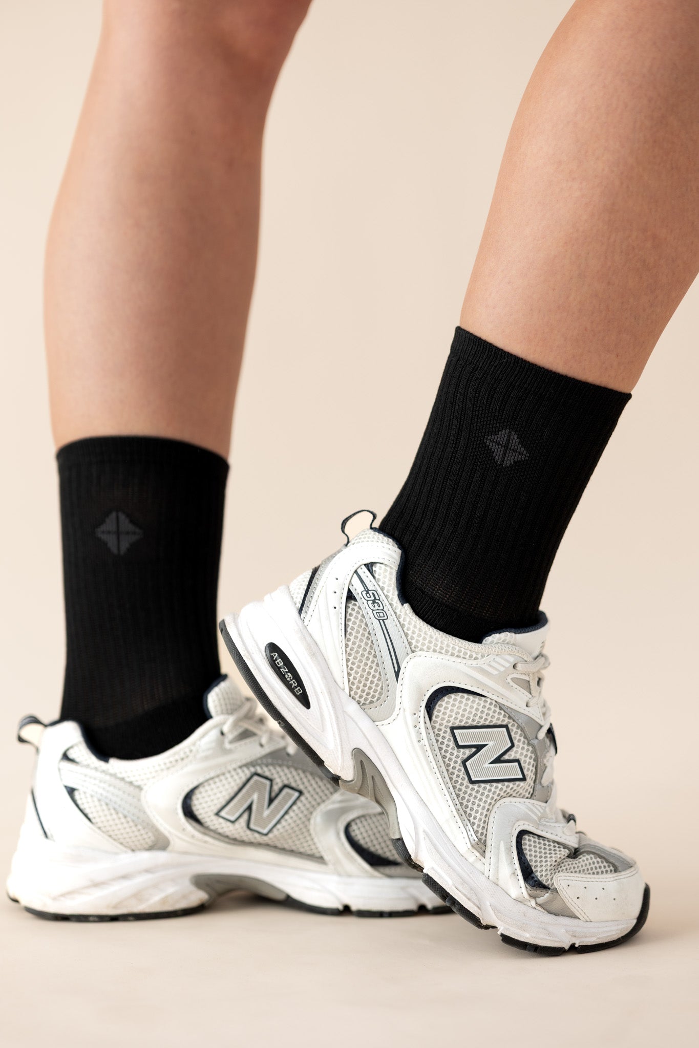 White sneakers with black socks on a beige background
