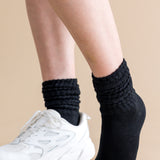 Person wearing black socks and white sneakers on a beige background