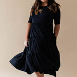 Female model wearing the Women’s Tiered Dress in Midnight with one hand in pocket