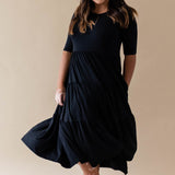 Female model wearing the Women’s Tiered Dress in Midnight with one hand in pocket